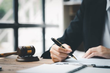 Bir avukat, elinde küçük bir çekiçle, ofisinde oturuyor. Mahkemede hakimlerin masasını yenmek için. Ve adalet terazileri, avukatlar müvekkilin imzalaması için bir sözleşme hazırlıyorlar..