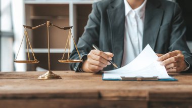 Bir avukat, elinde küçük bir çekiçle, ofisinde oturuyor. Mahkemede hakimlerin masasını yenmek için. Ve adalet terazileri, avukatlar müvekkilin imzalaması için bir sözleşme hazırlıyorlar..