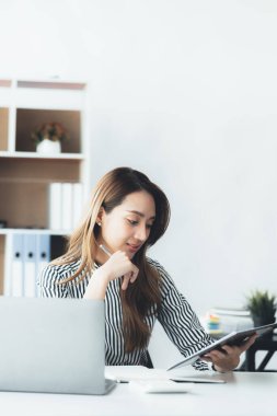 A businesswoman is checking company financial documents and using a laptop to talk to the chief financial officer through a messaging program. Concept of company financial management.