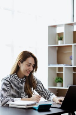 A businesswoman is checking company financial documents and using a laptop to talk to the chief financial officer through a messaging program. Concept of company financial management.