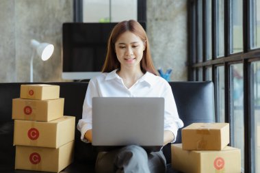 Güzel bir Asyalı işletme sahibi online bir dükkan açıyor, müşterilerin siparişlerini kontrol ediyor, bir kurye şirketi aracılığıyla mal gönderiyor, bir kadının online iş kurma kavramı.