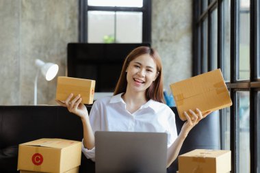 Güzel bir Asyalı işletme sahibi online bir dükkan açıyor, müşterilerin siparişlerini kontrol ediyor, bir kurye şirketi aracılığıyla mal gönderiyor, bir kadının online iş kurma kavramı.