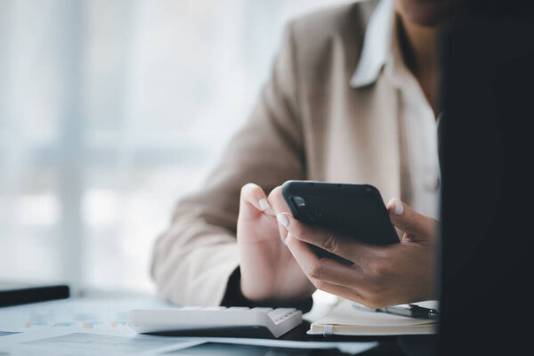 Бизнесмен, изучающая финансовую информацию с мобильного телефона, проверяет финансовые документы компании, является исполнительной женщиной стартап-компании. Концепция финансового управления.