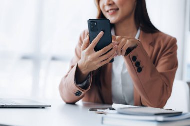 İş kadını cep telefonundan mali bilgilere bakıyor, şirketin mali belgelerini kontrol ediyor, yeni kurulan bir şirketin kadın yöneticisidir. Mali yönetim kavramı.