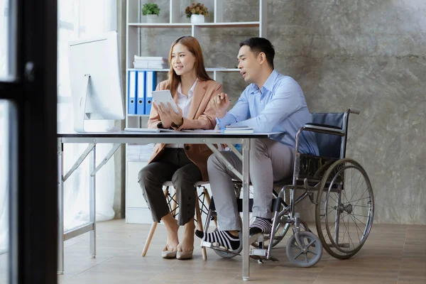 Man sits in a wheelchair and brainstorms with colleagues, conducts business, recruits people with disabilities to work, works with in-house teams and has people with disabilities as part of the team.