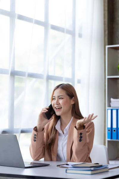 Beautiful Asian woman executives, business executives, marketing executives are talking on the phone with customers to contact the company for marketing. Marketing management concept.