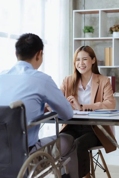 Man sits in a wheelchair and brainstorms with colleagues, conducts business, recruits people with disabilities to work, works with in-house teams and has people with disabilities as part of the team.