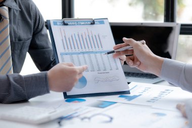 İki işadamı toplantı materyaline işaret ederek, ortak iş sorunlarını geliştirme ve çözme planında birlikte çalıştılar. Büyüme ve kalite için işletme yönetimi kavramı.