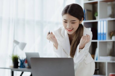 Woman gesturing and looking at the laptop, business woman checking company monthly sales and pretending to be happy as sales meet planned targets according to policy. Sales management concept.