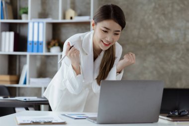 Woman gesturing and looking at the laptop, business woman checking company monthly sales and pretending to be happy as sales meet planned targets according to policy. Sales management concept.