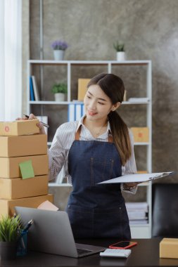 Güzel bir Asyalı işletme sahibi online bir dükkan açıyor, müşterilerin siparişlerini kontrol ediyor, bir kurye şirketi aracılığıyla mal gönderiyor, bir kadının online iş kurma kavramı.
