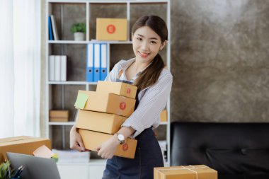 Güzel bir Asyalı işletme sahibi online bir dükkan açıyor, müşterilerin siparişlerini kontrol ediyor, bir kurye şirketi aracılığıyla mal gönderiyor, bir kadının online iş kurma kavramı.
