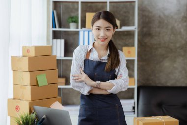 Güzel bir Asyalı işletme sahibi online bir dükkan açıyor, müşterilerin siparişlerini kontrol ediyor, bir kurye şirketi aracılığıyla mal gönderiyor, bir kadının online iş kurma kavramı.