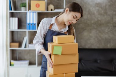 Güzel bir Asyalı işletme sahibi online bir dükkan açıyor, müşterilerin siparişlerini kontrol ediyor, bir kurye şirketi aracılığıyla mal gönderiyor, bir kadının online iş kurma kavramı.