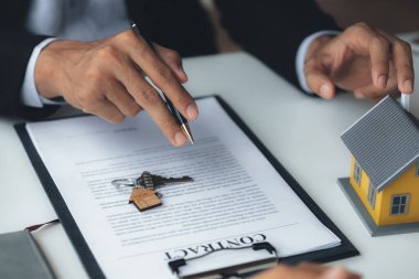 Rental company employee is discussing the details before the customer agrees to sign a rental contract, explaining the details and the terms and conditions of the rental. Real estate rental ideas.