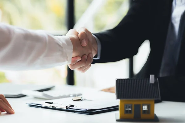 The salesperson of the housing estate in the project and the customer shake hands after successfully signing the contract. Concept of selling housing estates and real estate.