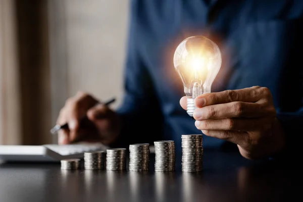Businessman Holds Glowing Light Bulb Top Highest Pile Coins Placing — ストック写真