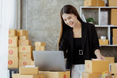 Güzel bir Asyalı işletme sahibi online bir dükkan açıyor, müşterilerin siparişlerini kontrol ediyor, bir kurye şirketi aracılığıyla mal gönderiyor, bir kadının online iş kurma kavramı.
