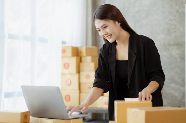Güzel bir Asyalı işletme sahibi online bir dükkan açıyor, müşterilerin siparişlerini kontrol ediyor, bir kurye şirketi aracılığıyla mal gönderiyor, bir kadının online iş kurma kavramı.