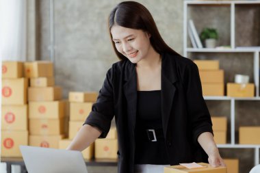 Güzel bir Asyalı işletme sahibi online bir dükkan açıyor, müşterilerin siparişlerini kontrol ediyor, bir kurye şirketi aracılığıyla mal gönderiyor, bir kadının online iş kurma kavramı.