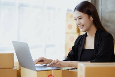 Güzel bir Asyalı işletme sahibi online bir dükkan açıyor, müşterilerin siparişlerini kontrol ediyor, bir kurye şirketi aracılığıyla mal gönderiyor, bir kadının online iş kurma kavramı.