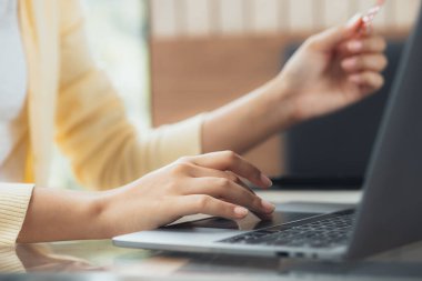 Laptop klavyesinde yazan bir kadın, bir internet alışveriş sitesinde sipariş vermek için kredi kartı bilgilerini dolduruyor. Çevrimiçi alışveriş ve kredi kartı ödeme kavramı.