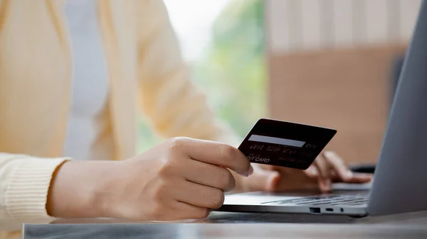Woman holding a credit card, she uses a credit card to pay for goods and services online, the concept of using a credit card for online shopping, ordering goods and services on the website.