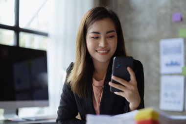 İş kadını cep telefonundan mali bilgilere bakıyor, şirketin mali belgelerini kontrol ediyor, yeni kurulan bir şirketin kadın yöneticisidir. Mali yönetim kavramı.