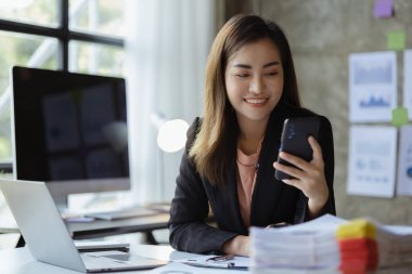 İş kadını cep telefonundan mali bilgilere bakıyor, şirketin mali belgelerini kontrol ediyor, yeni kurulan bir şirketin kadın yöneticisidir. Mali yönetim kavramı.