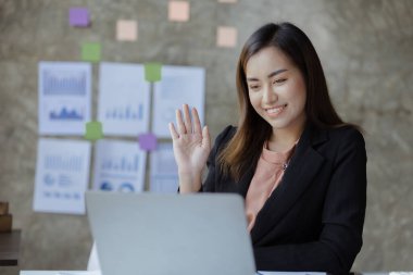 Güzel Asyalı iş kadını özel ofisinde oturuyor, eşiyle bilgisayarından video görüşmesi yapıyor, yeni başlayan bir şirketin kadın yöneticisidir. Mali yönetim kavramı