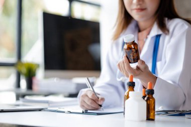An Asian female doctor works in the office of a hospital, she is a general practitioner, consulting patients and treatment specialists, providing targeted treatment, conceptual care and specialists.
