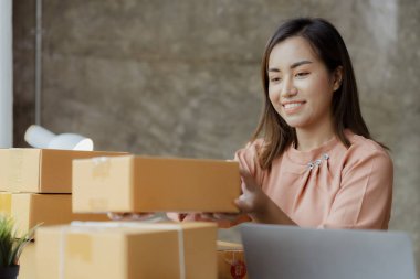 Güzel bir Asyalı işletme sahibi online bir dükkan açıyor, müşterilerin siparişlerini kontrol ediyor, bir kurye şirketi aracılığıyla mal gönderiyor, bir kadının online iş kurma kavramı.