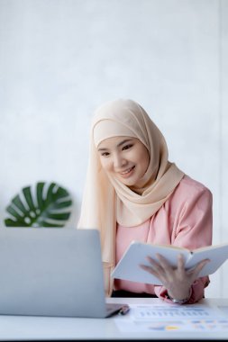 Asian women wearing hijab sitting in the office of a startup company, managed and operated by a young, talented working woman. The management concept drives the company of women leaders to grow.