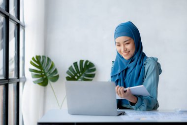 Asian women wearing hijab sitting in the office of a startup company, managed and operated by a young, talented working woman. The management concept drives the company of women leaders to grow.