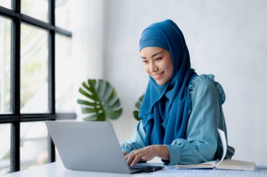 Asian women wearing hijab sitting in the office of a startup company, managed and operated by a young, talented working woman. The management concept drives the company of women leaders to grow.