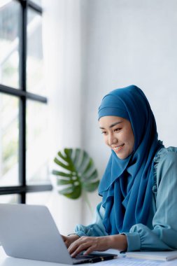 Asian women wearing hijab sitting in the office of a startup company, managed and operated by a young, talented working woman. The management concept drives the company of women leaders to grow.