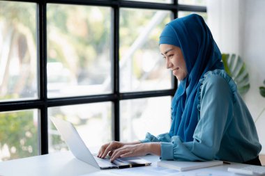 Asian women wearing hijab sitting in the office of a startup company, managed and operated by a young, talented working woman. The management concept drives the company of women leaders to grow.