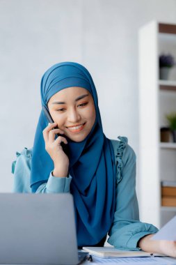 Asian women in hijab are talking on the phone, administration and operations from the new generation, smart working women. The management concept drives the company of women leaders to grow.