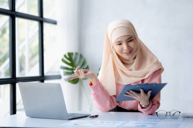 Asian women wearing hijab sitting in the office of a startup company, managed and operated by a young, talented working woman. The management concept drives the company of women leaders to grow.