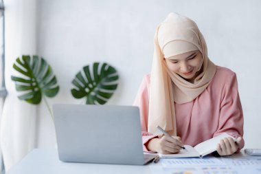 Asian women wearing hijab sitting in the office of a startup company, managed and operated by a young, talented working woman. The management concept drives the company of women leaders to grow.