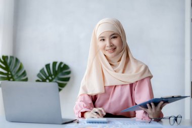 Asian women wearing hijab sitting in the office of a startup company, managed and operated by a young, talented working woman. The management concept drives the company of women leaders to grow.