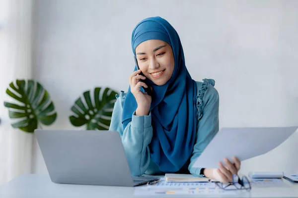 Asian women in hijab are talking on the phone, administration and operations from the new generation, smart working women. The management concept drives the company of women leaders to grow.