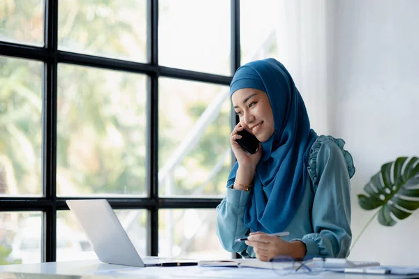 Asian women in hijab are talking on the phone, administration and operations from the new generation, smart working women. The management concept drives the company of women leaders to grow.