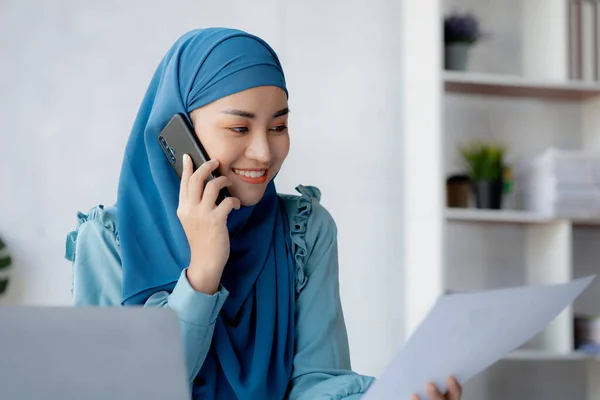 Asian women in hijab are talking on the phone, administration and operations from the new generation, smart working women. The management concept drives the company of women leaders to grow.