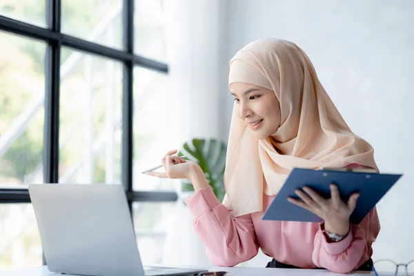 Asian women wearing hijab sitting in the office of a startup company, managed and operated by a young, talented working woman. The management concept drives the company of women leaders to grow.