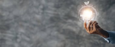 Person holding light bulb with earth hologram and renewable energy, hologram globe and wind energy used as pure renewable energy to reduce high cost oil, wind energy is natural energy. Global warming.