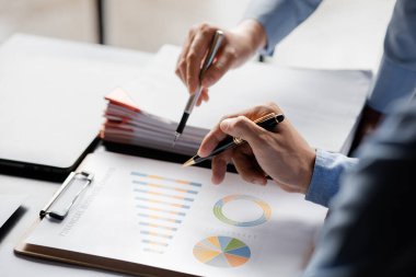 Company meeting room has businessmen and finance managers meeting together on finance topics, they are looking at information on documents and discussing together. Concept company financial management