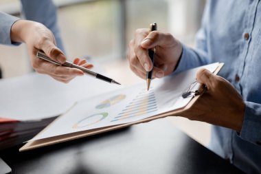 Company meeting room has businessmen and finance managers meeting together on finance topics, they are looking at information on documents and discussing together. Concept company financial management