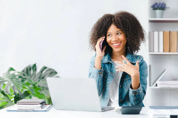 American teenage girl talking on the phone with classmates in white room, she is a student studying online at home, university student studying online, online web education concept.