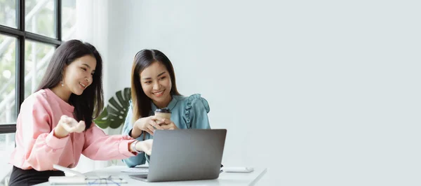 Atmosphere in the office of a startup company, two female employees are discussing, brainstorming ideas to working on summaries and marketing plans to increase sales and prepare reports to managers.